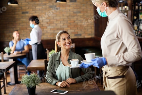 Preview: Happy woman enjoying while waitress is serving her coffee in a cafe,