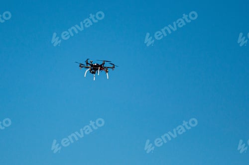 Preview: A camera drone flying in the blue sky. Copy space background