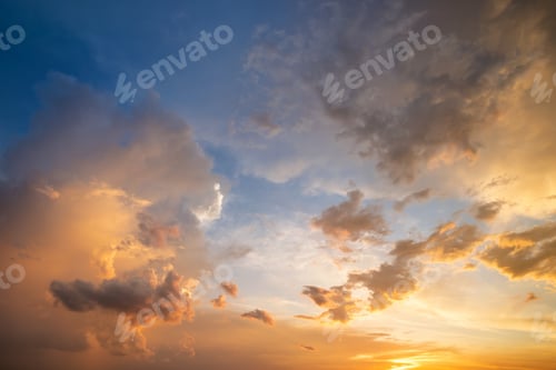 Preview: Dramatic sky at sunset with puffy clouds lit by orange setting sun