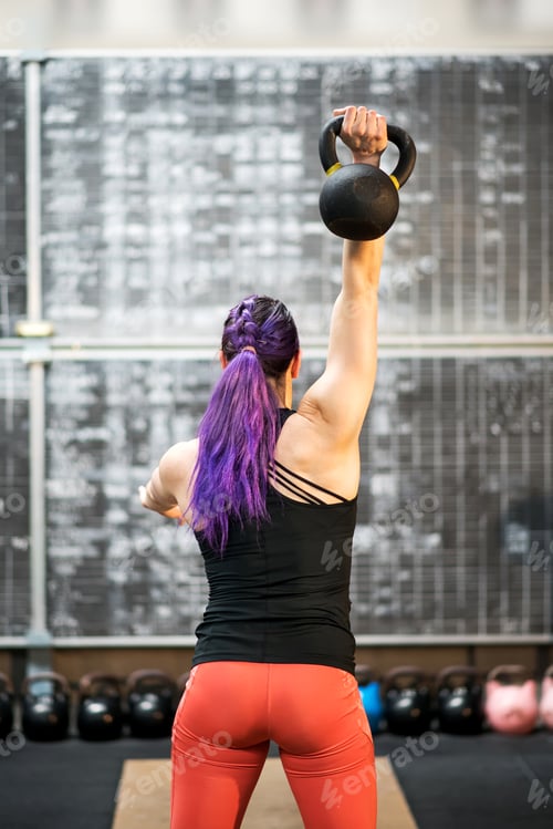 Preview: Rear view of a young woman swinging a kettlebell