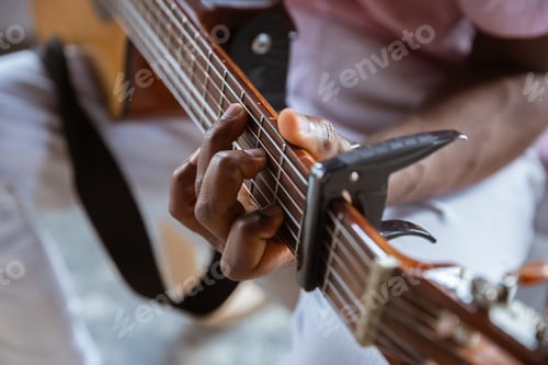 Preview: Close up of african-american musician playing guitar during online concert at home isolated and