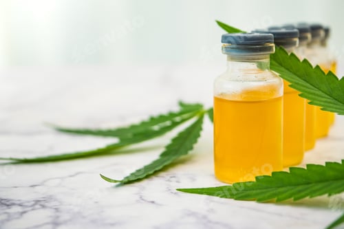 Preview: Cannabis oil in the vials with green leaves on marble table. Alternative medicine concept.