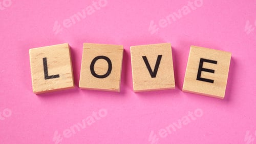 Preview: The word love from wooden cube letters on a pink background