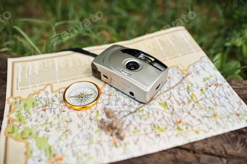 Preview: Close-up photo of compass laying on the map next to the camera.
