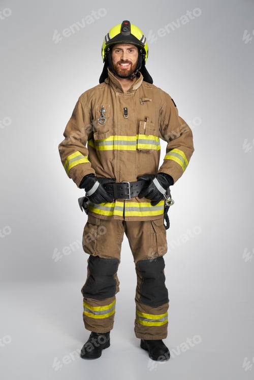 Preview: Smiling bearded firefighter with hands on belt, posing in studio.
