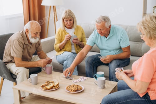 Preview: Group of senior people laughing while relaxing at home and playing cards.
