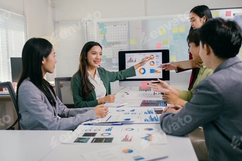 Preview: Asian business team analyzing charts on computer screen and discussing during meeting
