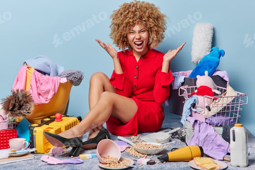 Preview: Irritated curly lady keeps palms raised and exclaims angrily wears red dress black high heeled shoes