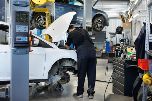 Vista previa: Close-up of a worker, a repairman, repairing a car. The open hood of the car in the repair garage.