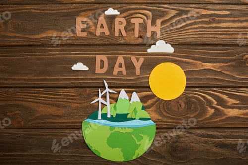 Preview: top view of paper cut planet with renewable energy sources and letters on wooden background, earth