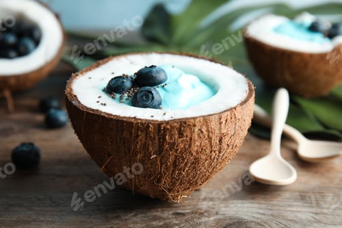 Preview: Coconut with spirulina smoothie on wooden table, closeup