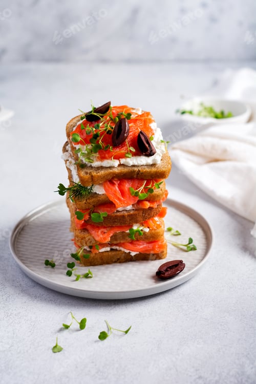 Preview: Sandwiches with smoked pink salmon olives, kalamata, microgreens and cream cheese on gray ceramic pl