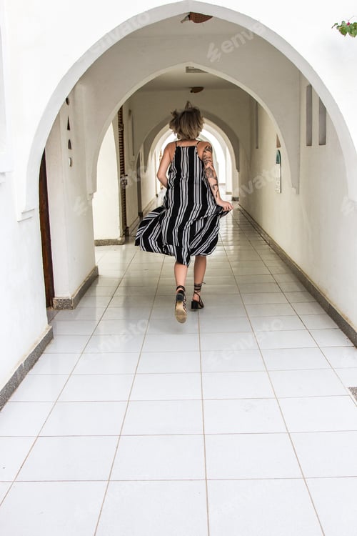 Preview: back view of young woman in dress running at corridor
