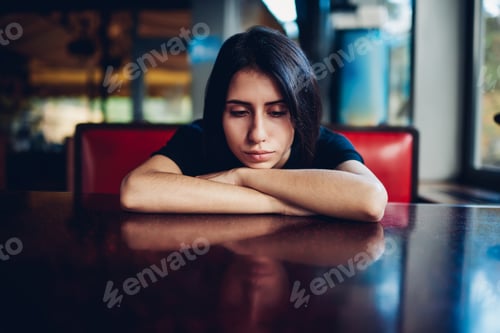 Preview: Sad woman leaning on table in cafe