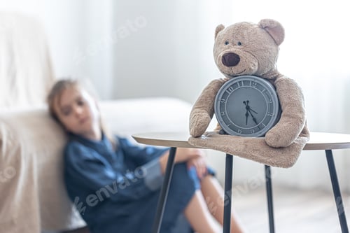 Preview: Teddy bear with alarm clock on a blurred background of the children's room.