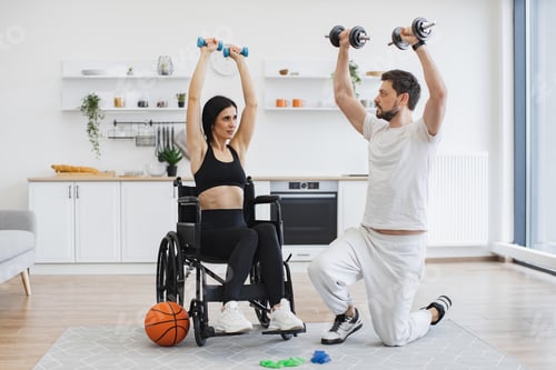 Preview: Physiotherapist showing adult woman in wheelchair how do exercises.