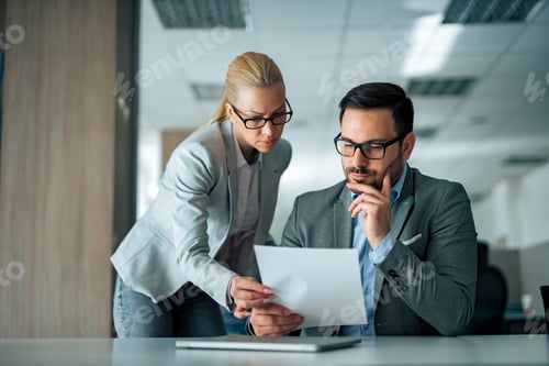 Preview: Portrait of serious business people looking at paper document.
