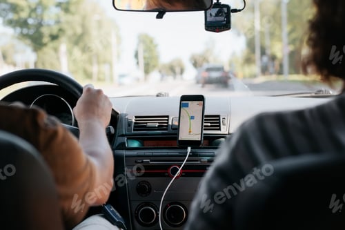 Preview: Rear view of a couple of people driving a car using a map navigator mobile app.