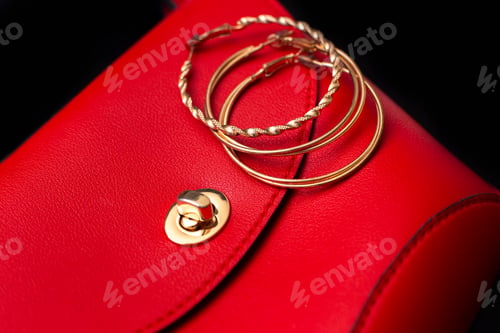 Preview: Gold ring earrings lie on a red leather bag