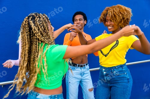 Preview: Happy multiracial friends dancing together holding hands outdoors