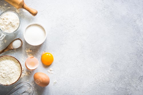 Preview: Baking background ingredients. Flour, sugar, eggs and rolling pin at light stone table.