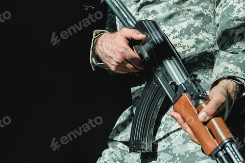 Preview: cropped shot of soldier holding rifle isolated on black