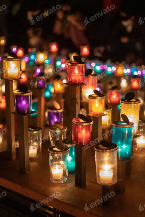 Preview: Vertical shot of burning candles in colorful glass candlesticks