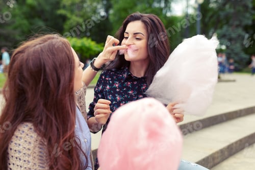 Preview: Two young women share cotton candy outdoors