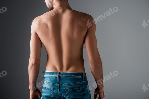 Preview: Back view of sexy shirtless man in jeans on grey