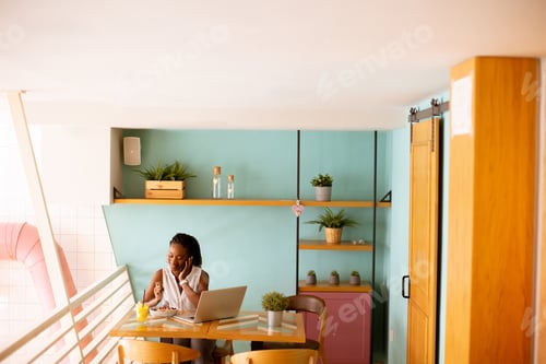 Preview: Young black woman drinking coffee while working on laptop in the cafe