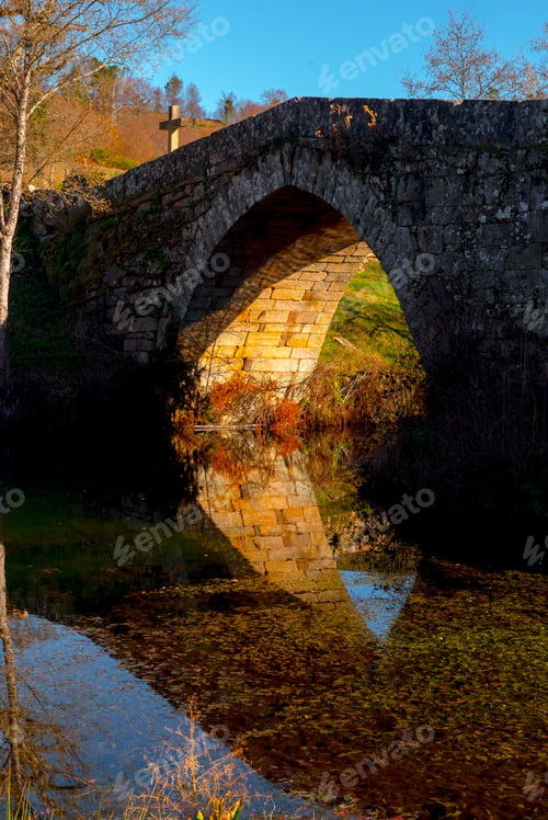 Preview: Old bridge over calm river in autumn countryside