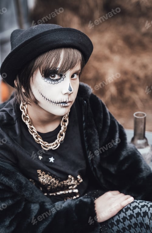 Preview: Beautiful scary little girl celebrating halloween. Terrifying black, white half-face makeup and witc