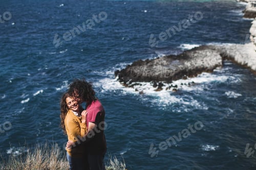 Preview: Couple with curly hair hugging at the coast with beautiful ocean view