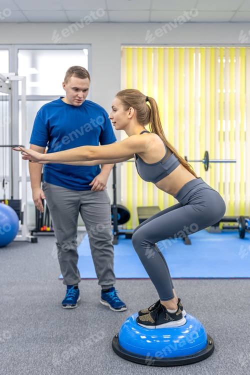 Preview: Doctor and female patient train balance on bosu in rehab gym. Bosu balance.