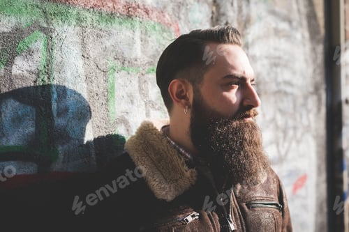 Preview: Young bearded man by graffiti wall