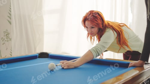 Preview: Concentrated woman hitting a pool ball playing with friends
