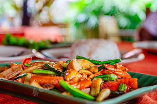 Preview: Delicious stir-fried vegetables with chicken served on a plate at a vibrant outdoor restaurant