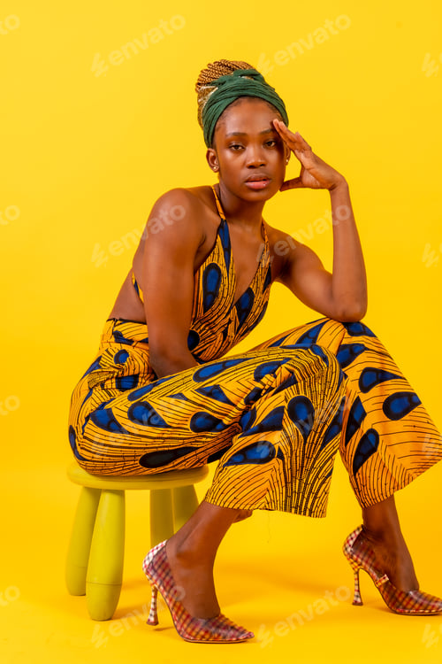 Preview: A person woman of black ethnicity with traditional costume yellow background, sitting in a fashion