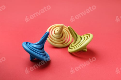 Preview: Many colorful spinning tops on red background, closeup