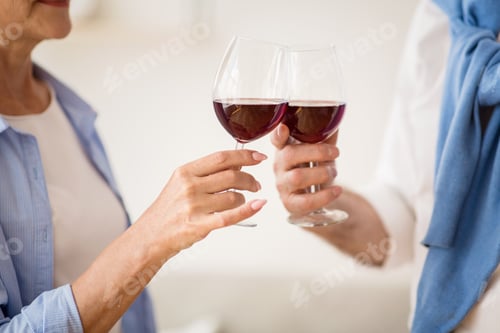 Preview: Mature couple clinking glasses with red wine at home