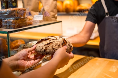 Preview: Customer hands in the bakery shop buying a loaf from the baker in the workshop workshop