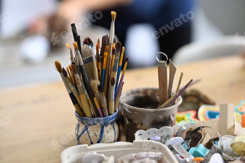 Preview: Ceramics making equipment with paint brushes, pottery shaping tools on wooden table.