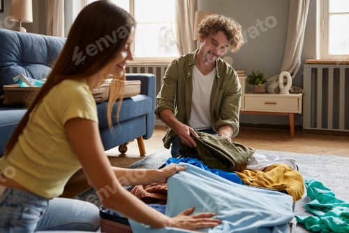 Preview: Young couple folding travel suitcase preparing for honeymoon at resort