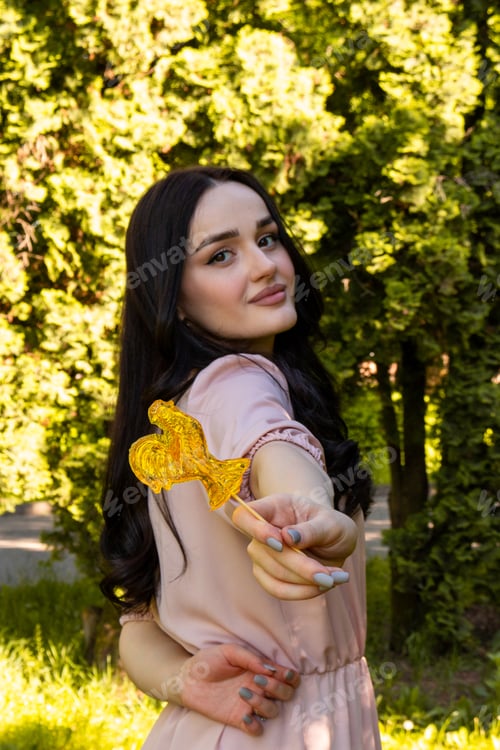 Preview: A young beautiful girl in a pale pink dress on the background of a green park