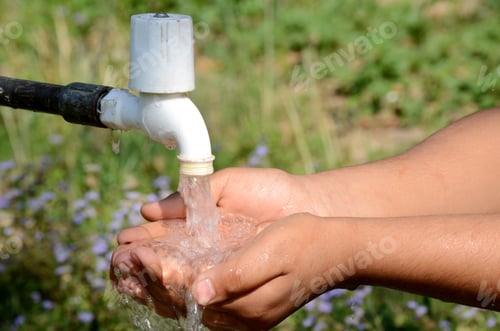 Preview: Closeup shot of a person washing their hands with an outdoor tap