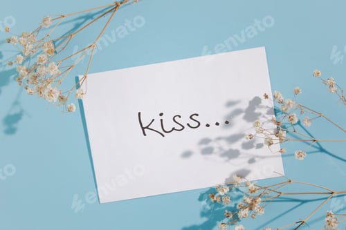 Preview: invitation card with gypsophila on blue background. Flat lay, top view, copy space. word kiss