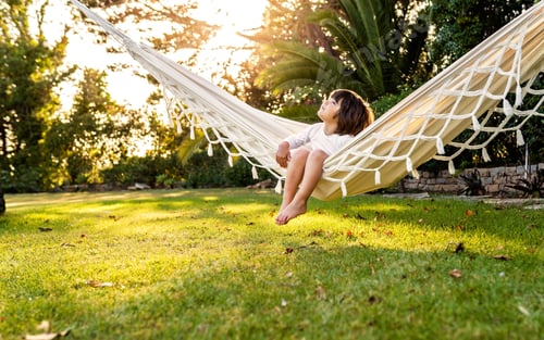 Preview: Cute little barefoot boy relaxing sitting in hammock. Child summer holidays healthy lifestyle