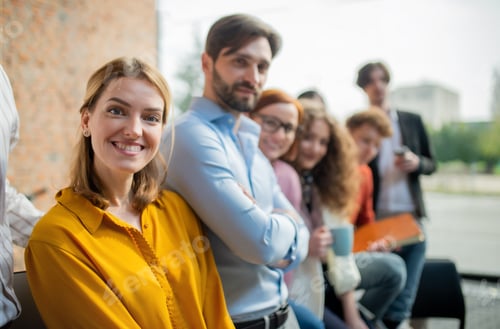 Preview: Portrait of young businesswoman with group of entrepreneurs indoors in office, looking at camera