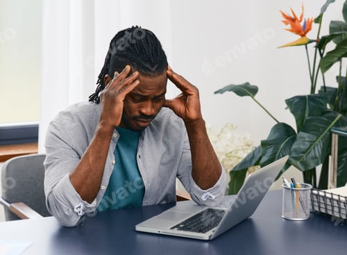 Preview: African American man works at home workplace using laptop gets stress from distance work and lack o