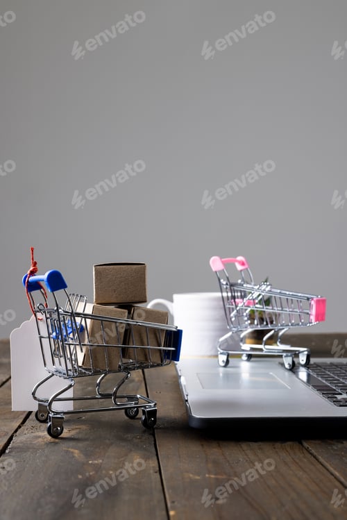 Preview: Composition of shopping carts with boxes and laptop on gray background